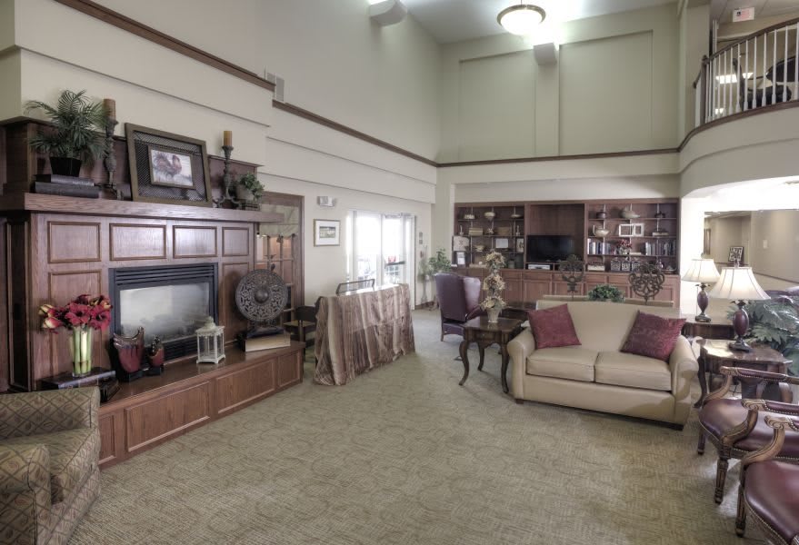 A spacious living room with a large sofa, bookshelves, and a television.
