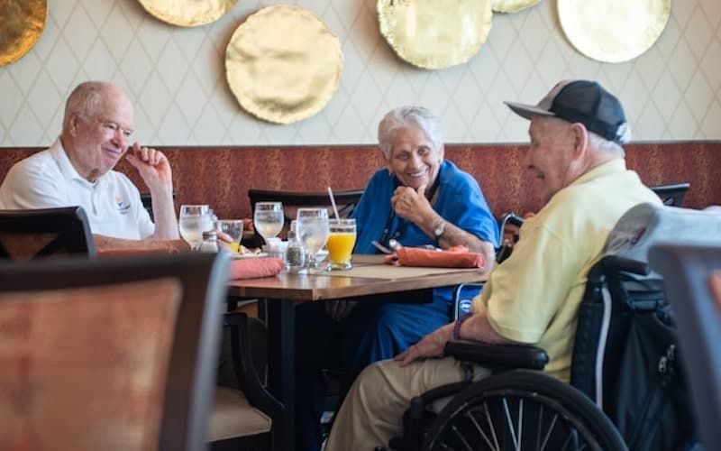 A group of elderly people enjoying a conversation at a restaurant table.