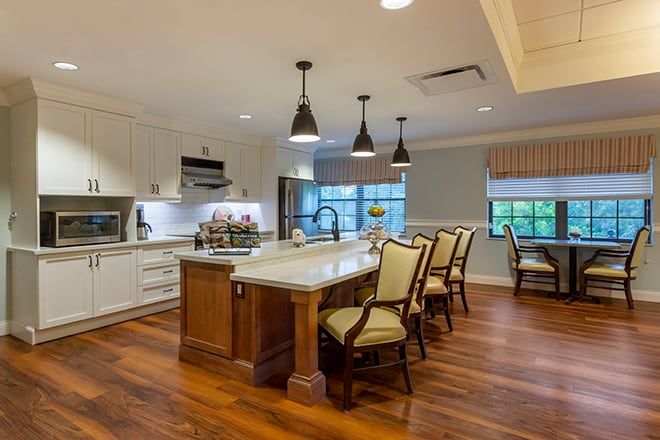 A modern kitchen with a central island, wood flooring, and stylish lighting.