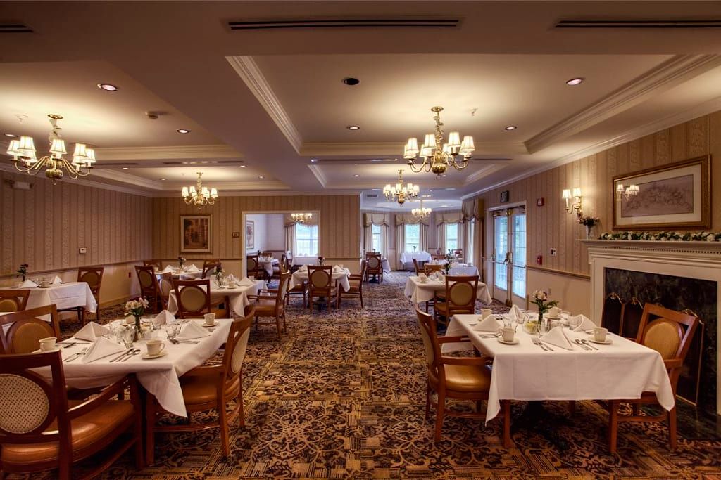 An elegant dining room with neatly arranged tables and chandeliers.