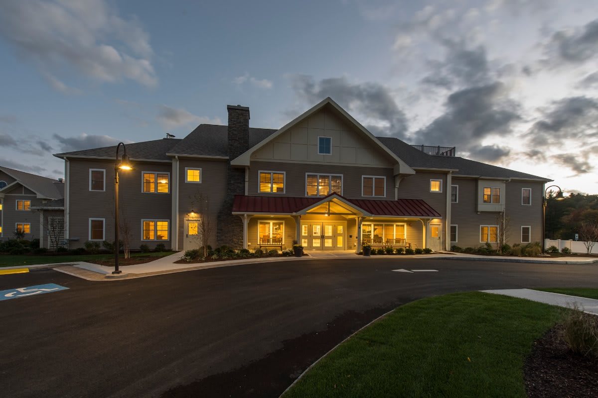 A warmly lit building at dusk with a cloudy sky backdrop.