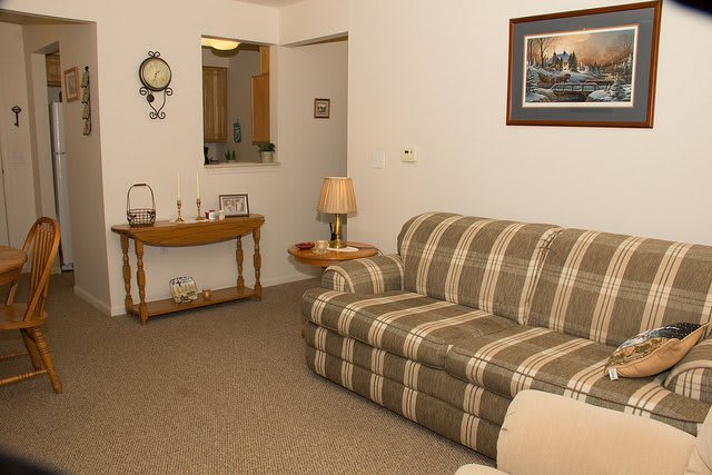 A cozy living room with a plaid sofa, a side table, and decorative items.