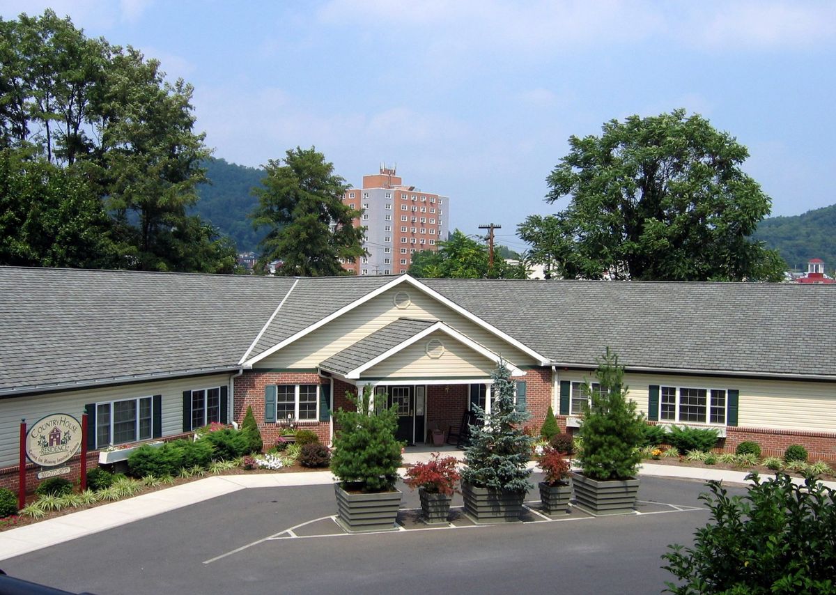 A residential building with a landscaped garden in front, surrounded by trees.