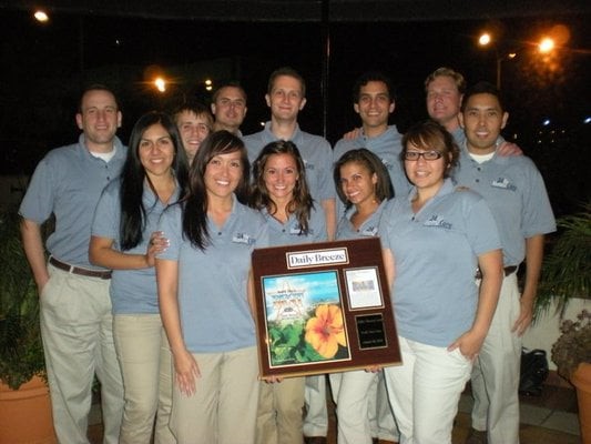 A group of people standing together, holding an award plaque.