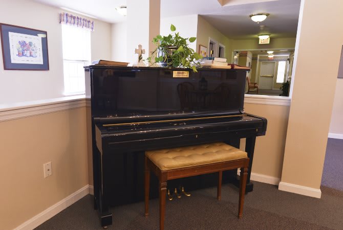 An upright piano with a wooden bench in a cozy indoor setting.