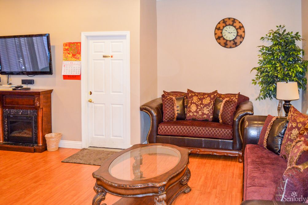 A cozy living room featuring a decorative sofa with patterned cushions, a wooden coffee table, and a wall clock.