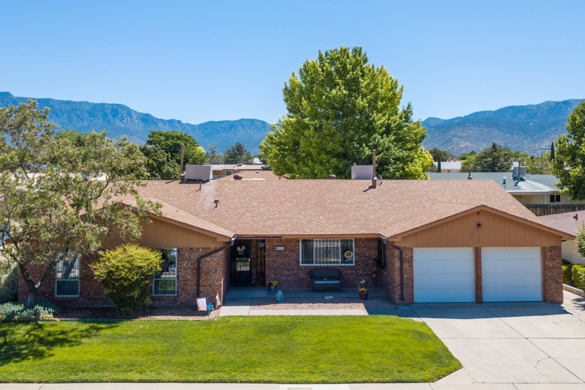 A suburban house with a spacious front yard and a backdrop of mountains.