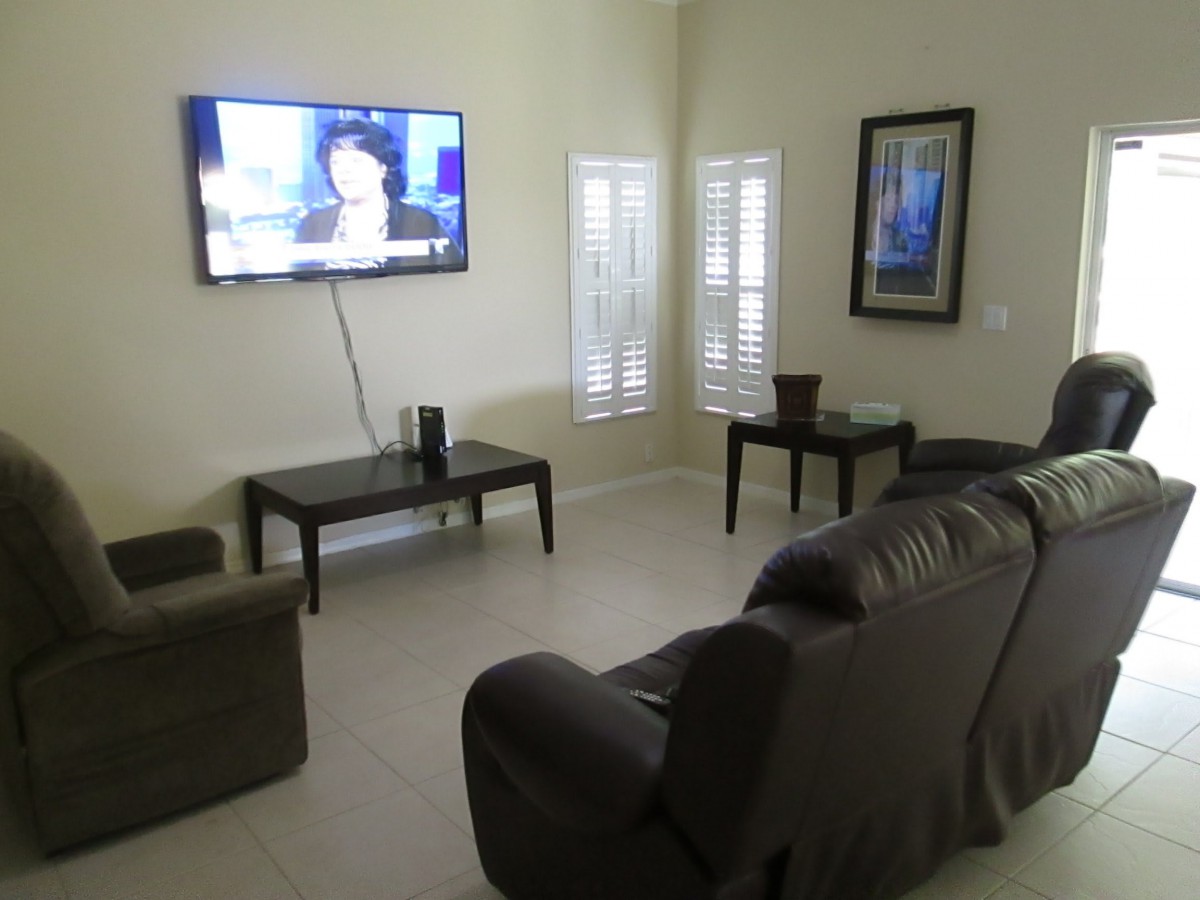 A modern living room with a wall-mounted TV and comfortable seating.