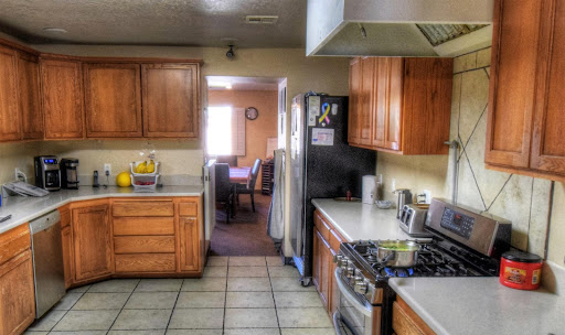 A modern kitchen with wooden cabinets, a gas stove, and a view into the dining area.
