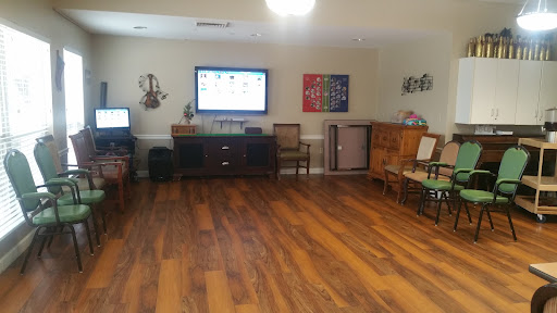 A spacious living room featuring a TV, various pieces of furniture, and wooden flooring.