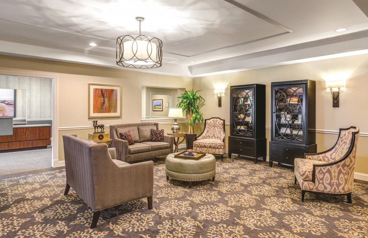 A cozy and elegantly furnished living room with comfortable seating, decorative lighting, and artwork on the walls.