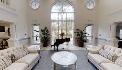 A luxurious lobby featuring a grand piano and elegant seating area with large windows.