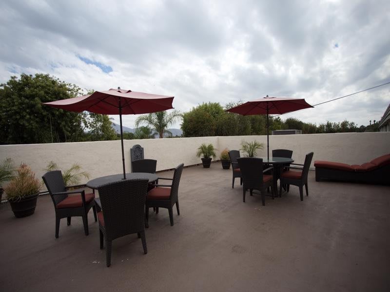 A spacious outdoor patio area featuring tables and chairs under red umbrellas.