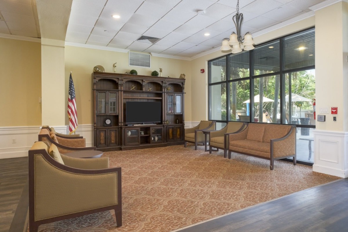 A spacious waiting room with seating, a television, and large windows letting in natural light.