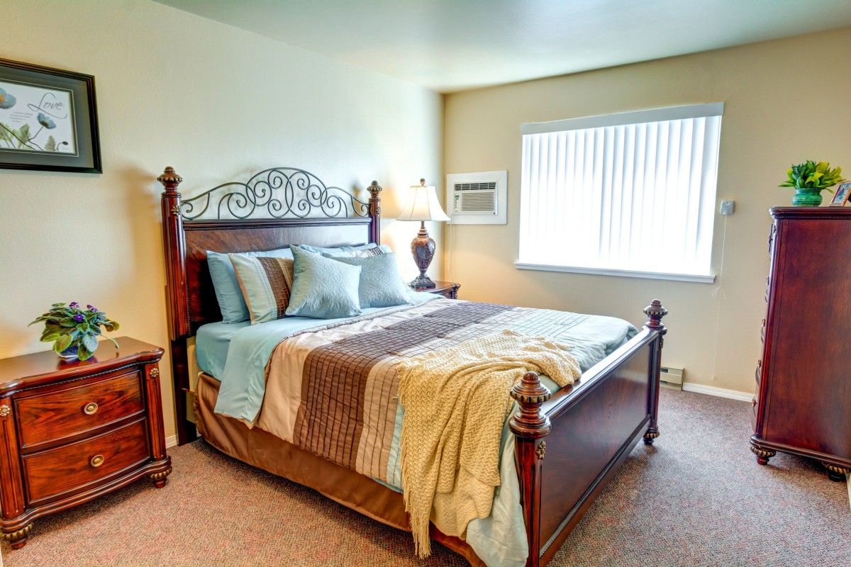 A cozy bedroom with a large bed, decorative pillows, and a bedside lamp.