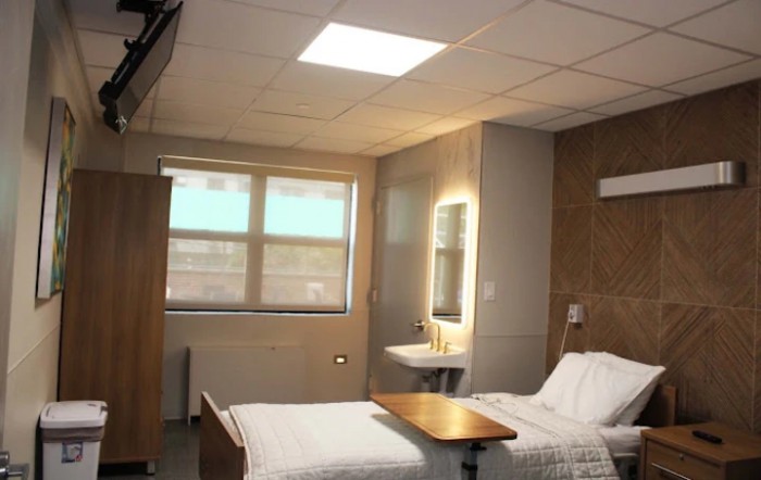 A clean and modern hospital room with a single bed, window, and soft lighting.