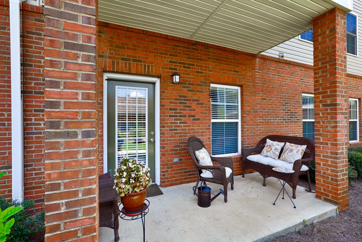 A cozy outdoor patio with wicker furniture and brick walls.