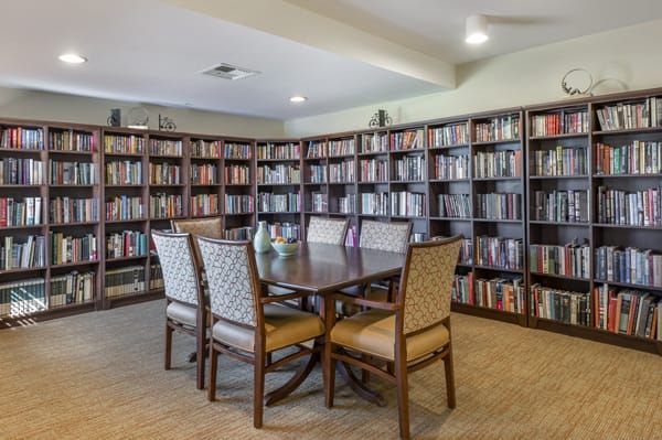 A cozy library with bookshelves surrounding a table and chairs.