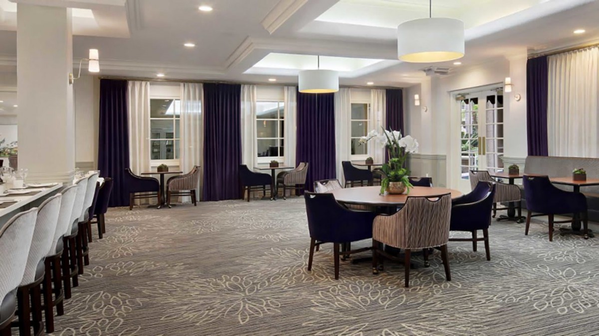 A modern dining area with elegant tables, upholstered chairs, and stylish lighting.