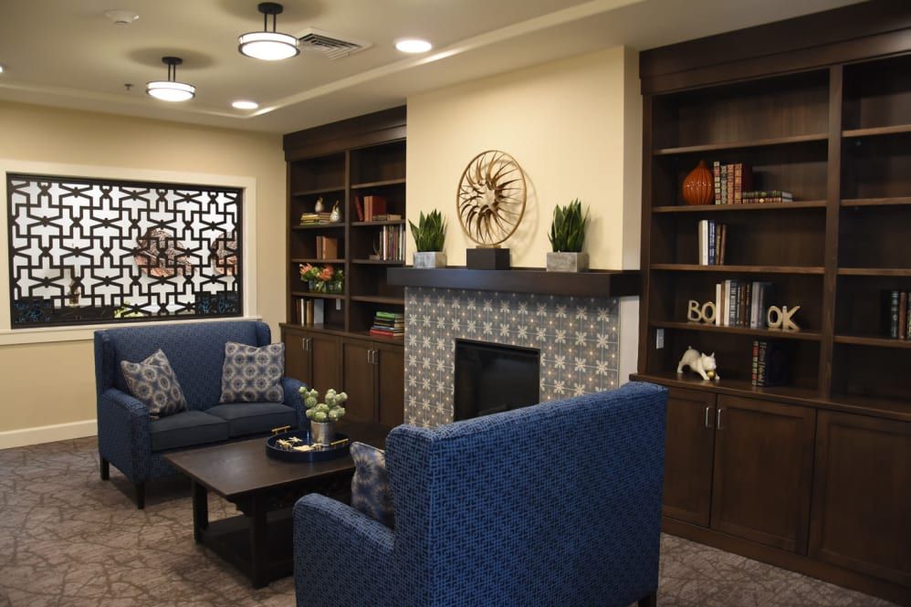 A cozy and modern living room with blue sofas, a fireplace, and built-in shelves.