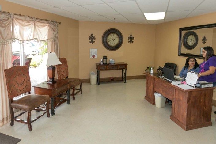 An office reception area with a desk, chairs, and wall decorations.