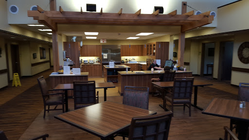 A spacious dining area featuring wooden furniture and a modern kitchen setup.