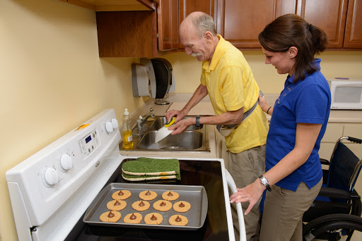 An elderly man and a caregiver working together in the kitchen, preparing cookies.