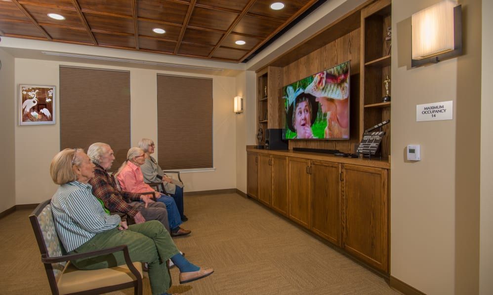 A group of elderly people watching television in a cozy room.