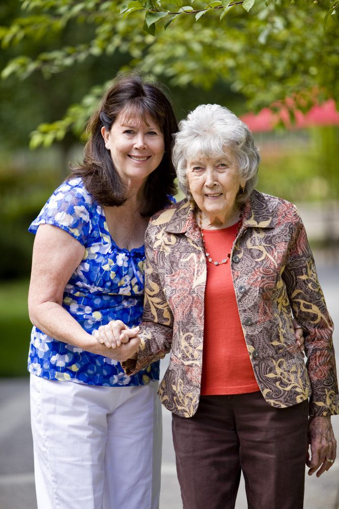 Two women smiling and holding hands outdoors.
