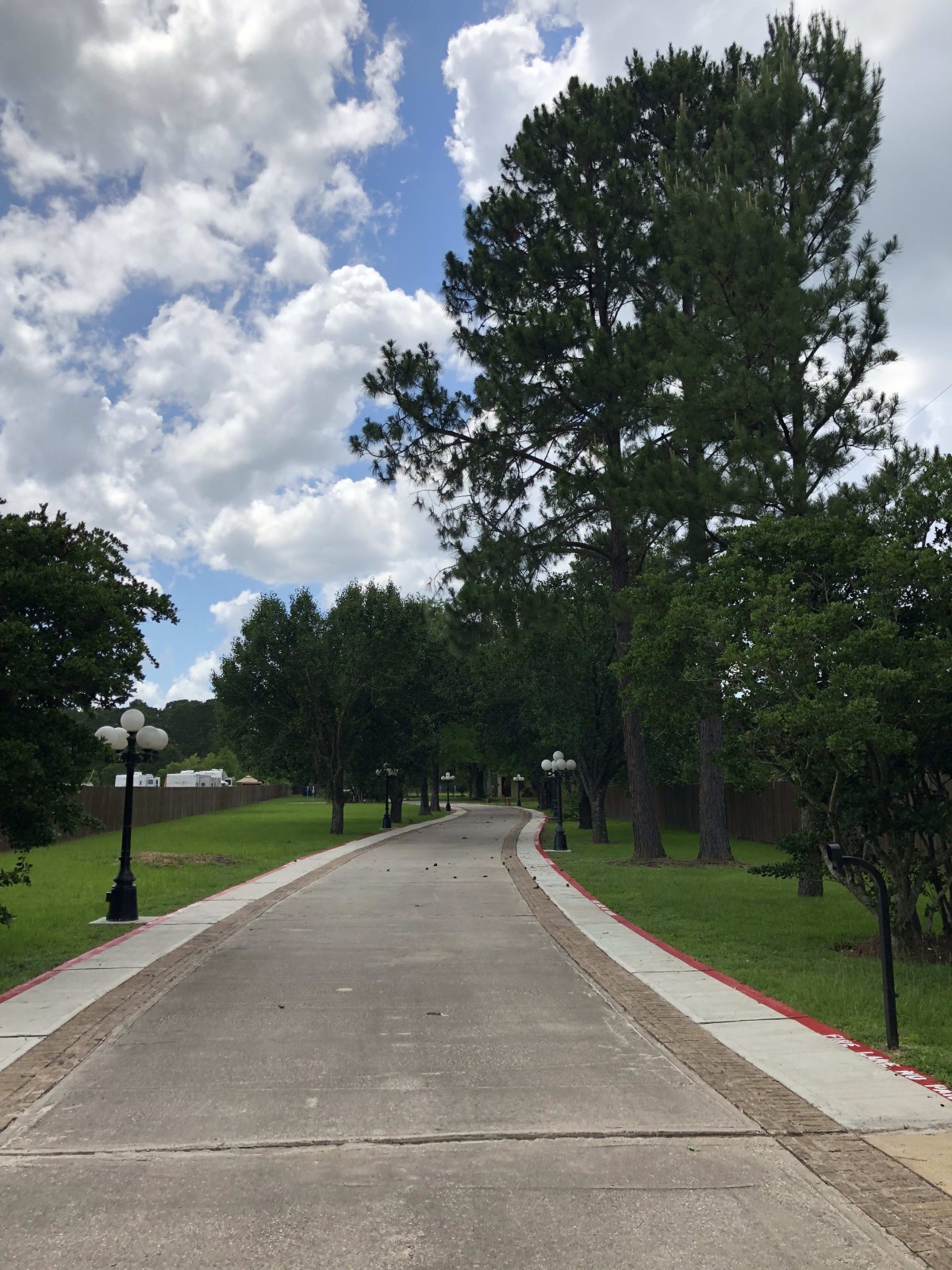 A scenic road lined with trees under a partly cloudy sky.