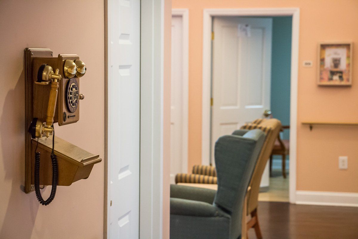 A vintage-style hallway with an old-fashioned telephone and armchair in pastel-colored surroundings.