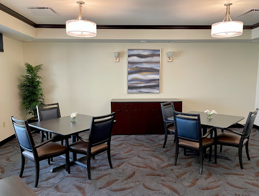 A modern dining area featuring tables and chairs, complemented by decorative artwork and indoor plants.