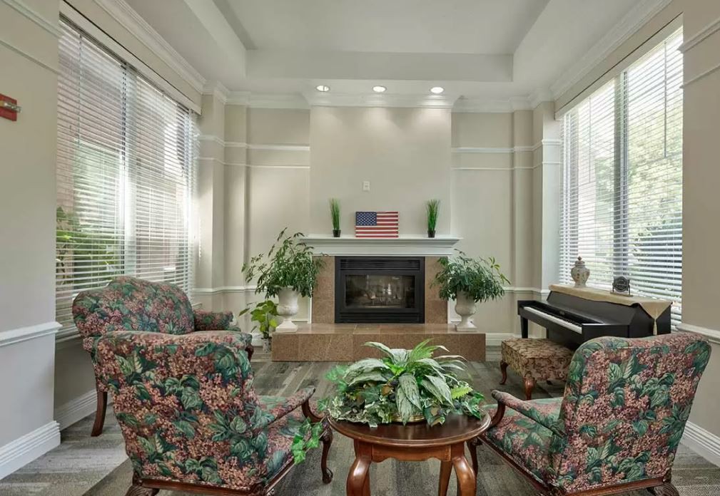 A cozy living room with a fireplace, plants, and comfortable seating.