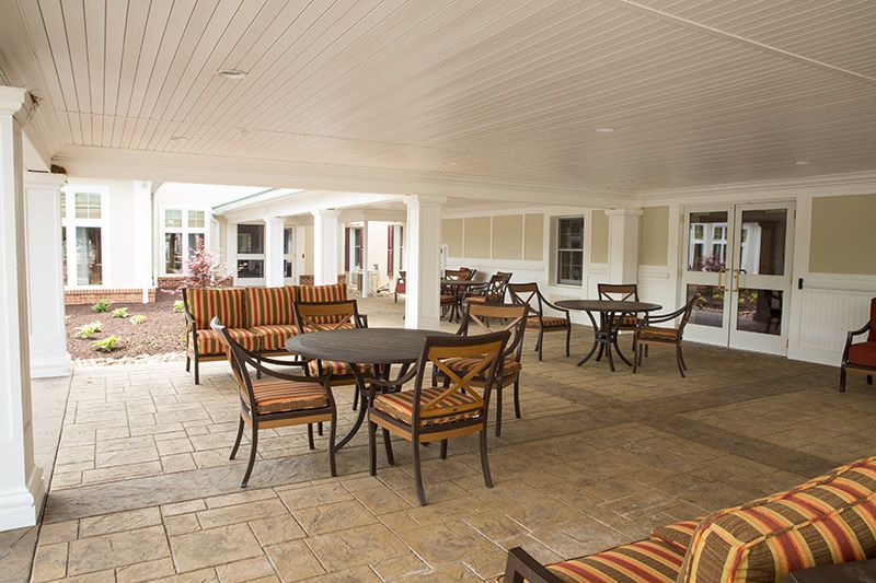 A spacious outdoor patio with several tables and chairs under a covered area.