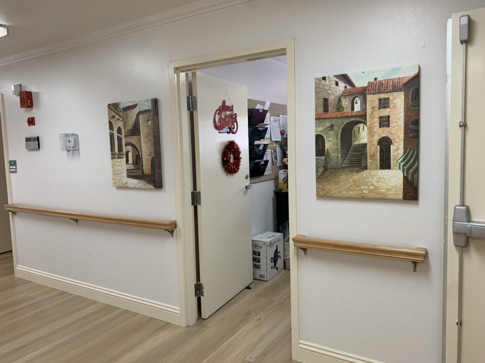 A hallway with paintings on the walls and a partially open door leading to another room.