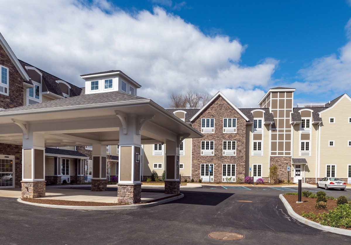 Modern residential building with a covered entrance and clear sky.