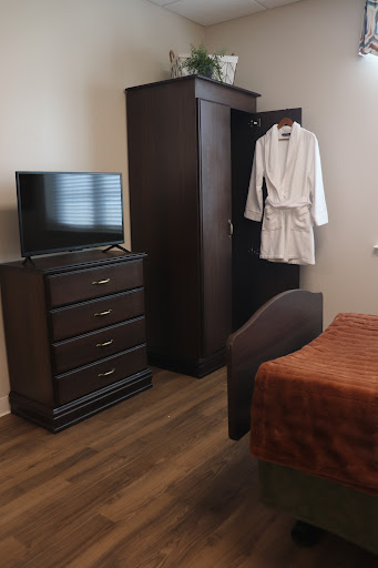 A cozy hotel room featuring a dresser, television, and a robe hanging on the door.