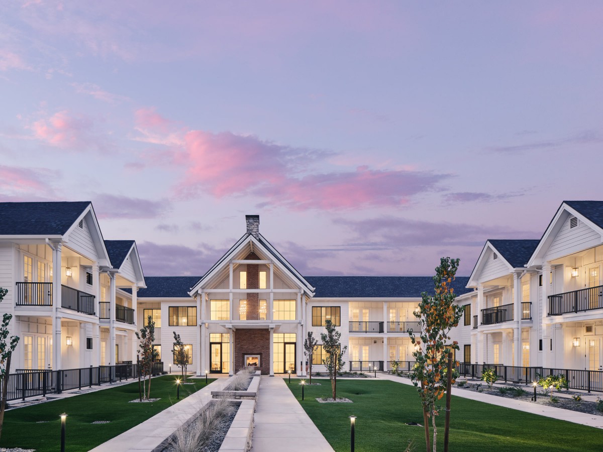 A modern residential building with a beautifully landscaped garden at dusk.