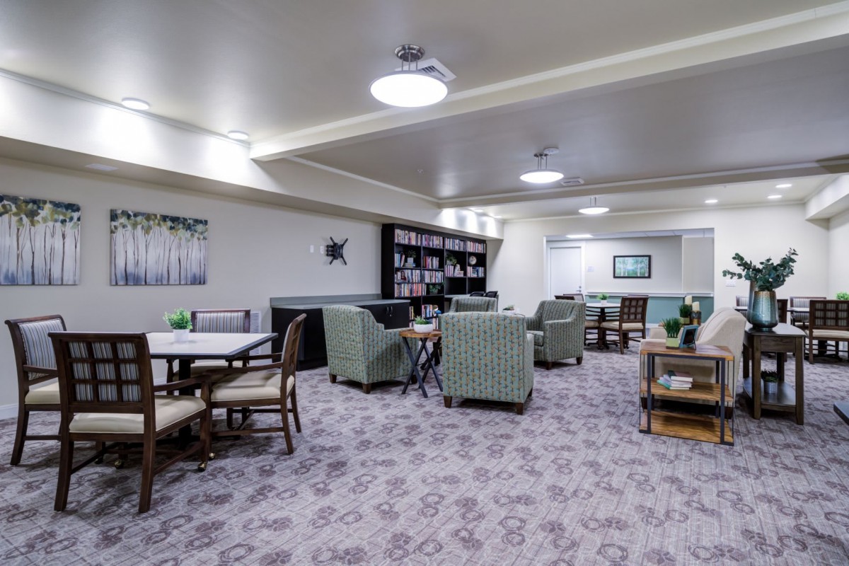 A cozy lounge area with comfortable seating, tables, and bookshelves.