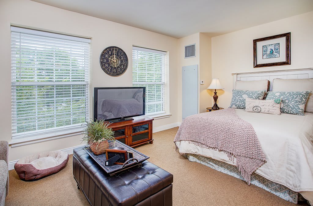 A cozy bedroom with a large bed, television, and stylish decor.