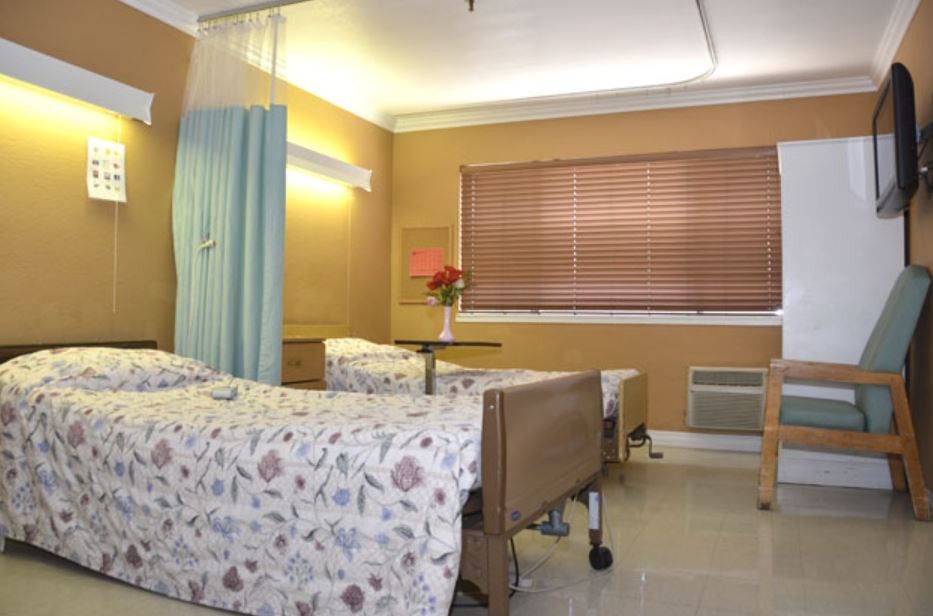 A tidy hospital room with two beds, separated by a curtain and lit by soft lighting.