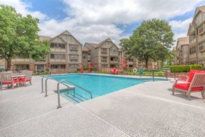 A residential complex with a swimming pool surrounded by apartment buildings and trees.