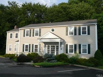 A colonial-style house with green shutters and a well-maintained landscape.