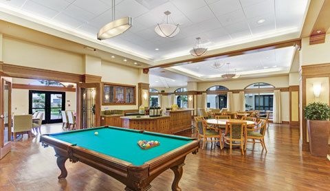 A stylish game room featuring a billiards table and elegant wooden furnishings.