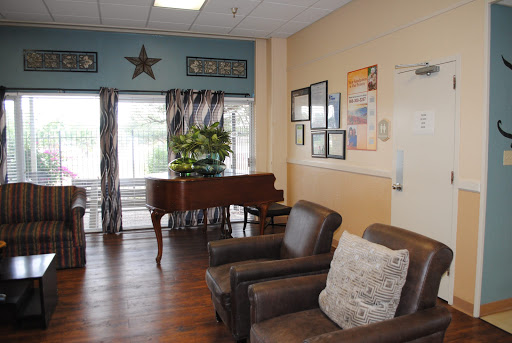 A cozy lounge area featuring comfortable seating and a piano, adorned with decorative elements and natural light.