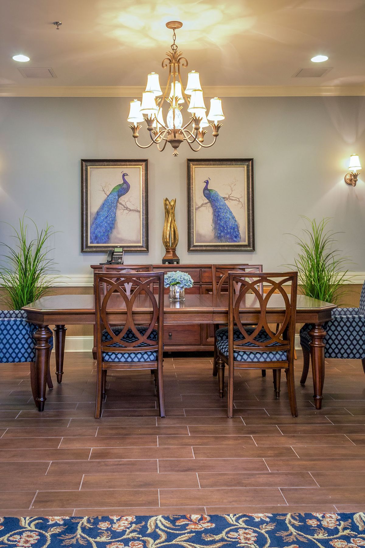 A beautifully decorated dining room featuring elegant wooden furniture, framed artwork, and a chandelier.