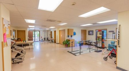 A spacious and well-lit rehabilitation center with parallel bars for therapy exercises.