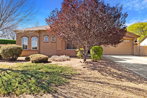 A cozy residential house surrounded by a well-maintained front yard and a beautiful tree.