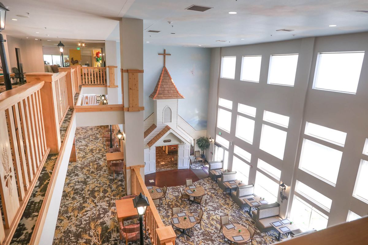 A spacious interior featuring a small chapel-like structure, large windows, and seating arrangements.