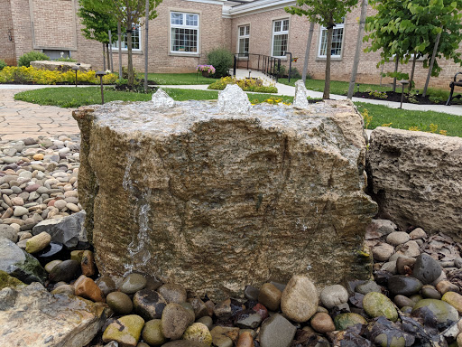 A tranquil water feature made of natural rock, surrounded by decorative pebbles in a landscaped garden.